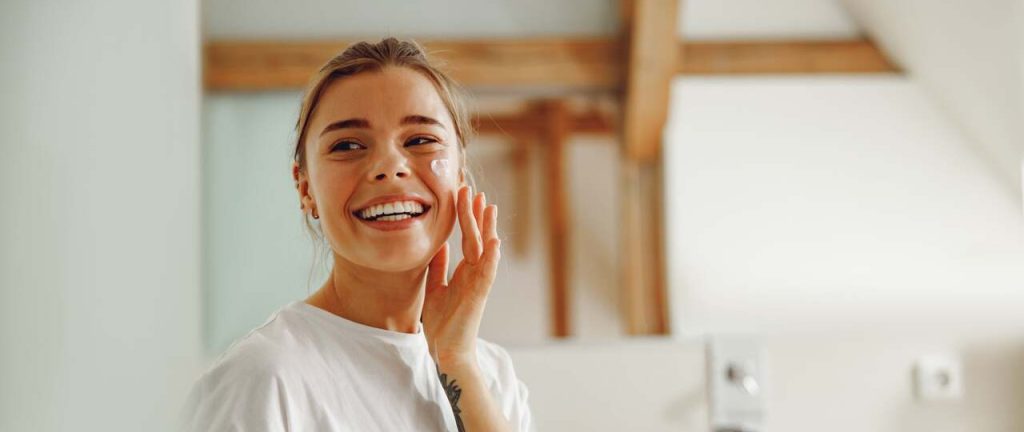 chica aplica crema para piel grasa